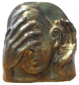 Photo des Preises, einer Bronzeskulptur, die ein Frauengesicht zeigt. Die eine Hand der Frau liegt hinter ihrem Ohr, mit der anderen bedeckt sie ihre Augen.